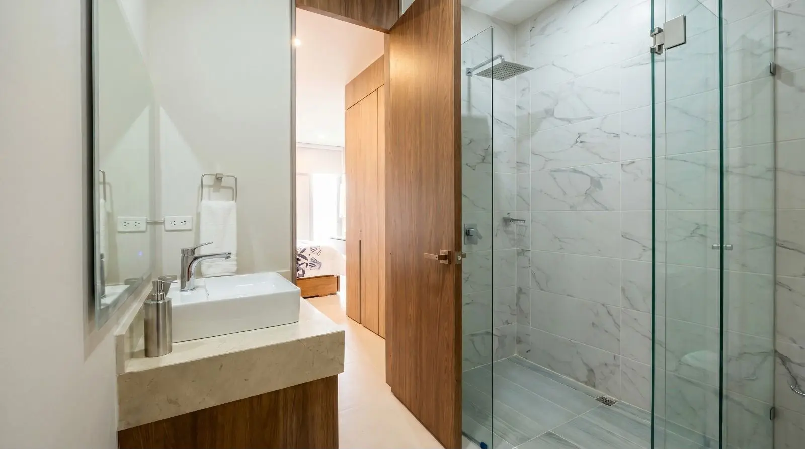 Baño con ducha y división en vidrio.