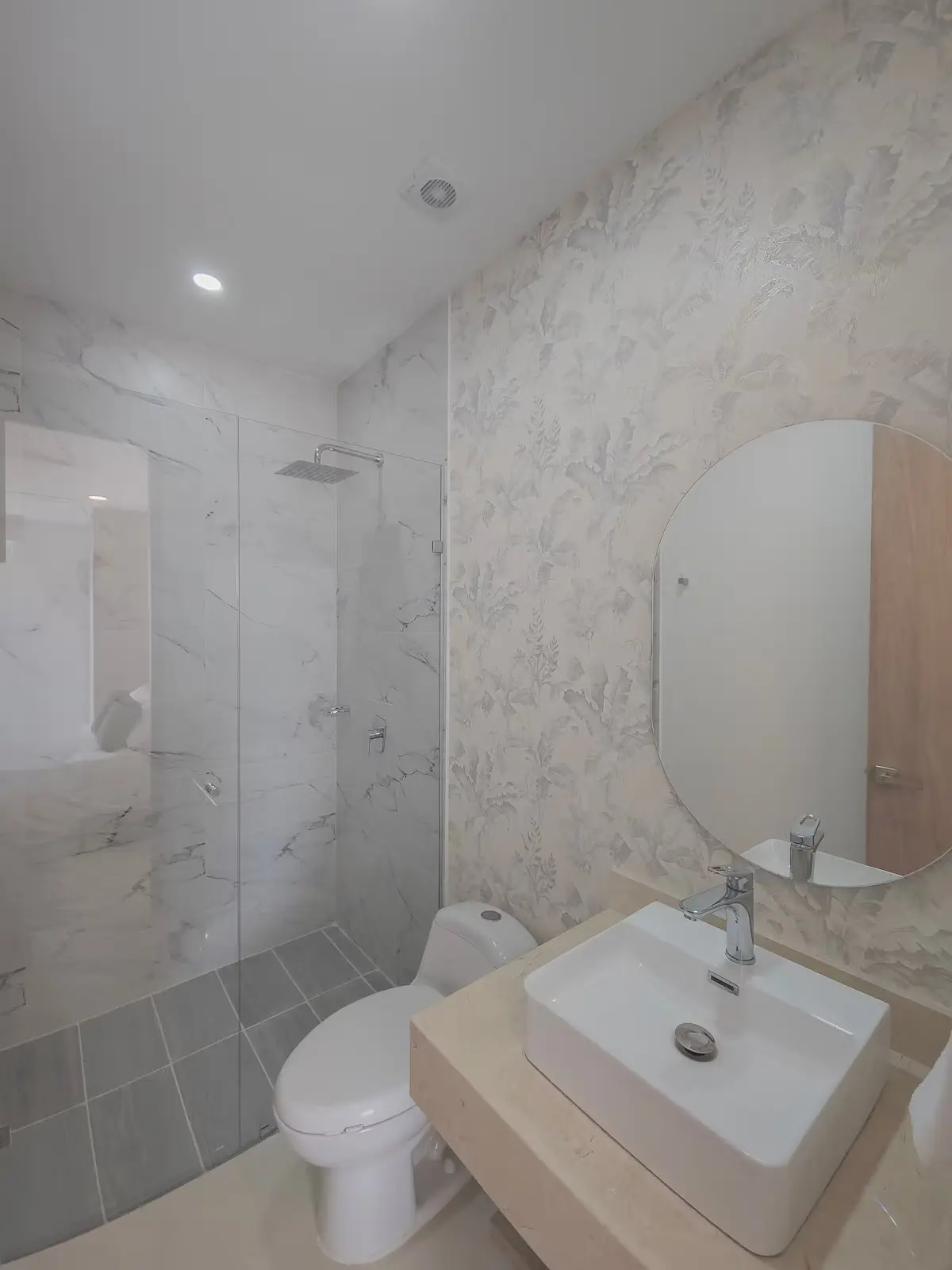 Baño con ducha y división en vidrio.