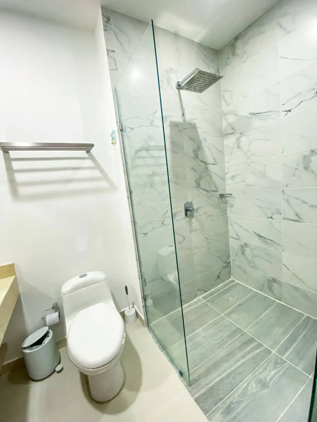 Baño privado con ducha y división en vidrio.