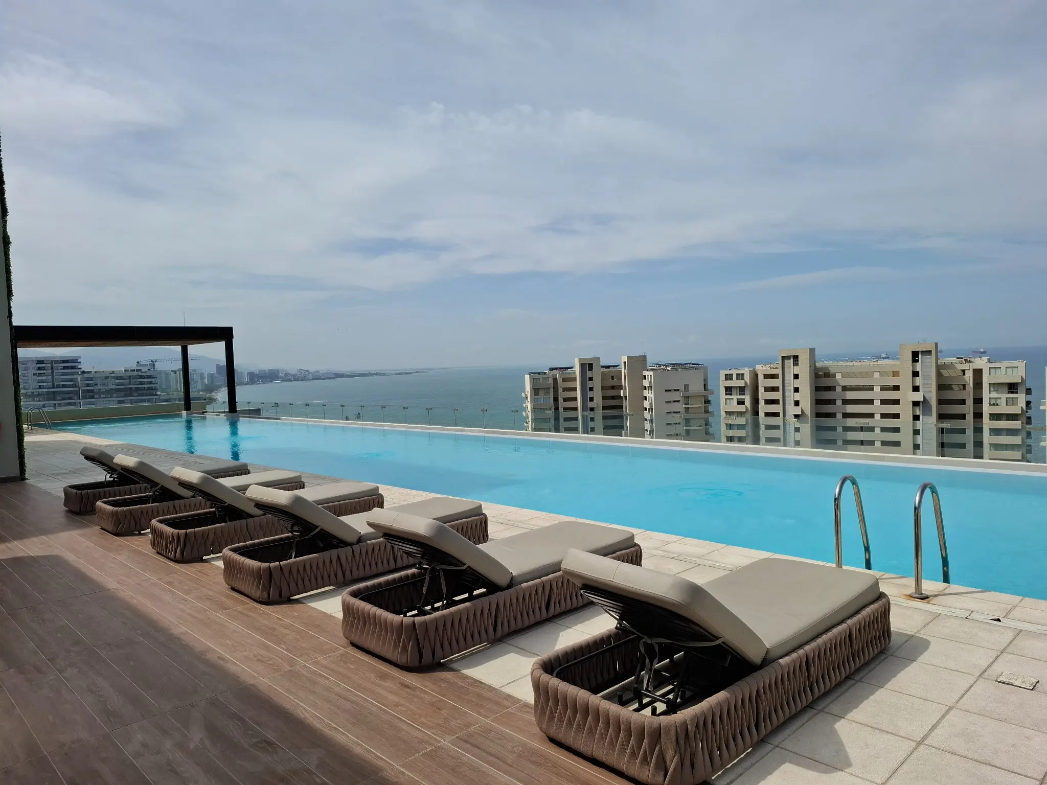 Piscina del piso 16 con sillas asoleadoras y vista al mar